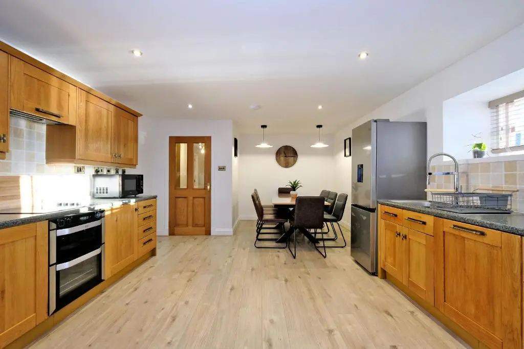 a kitchen with wooden cabinets and a table with chairs at Rosebrae in Insch