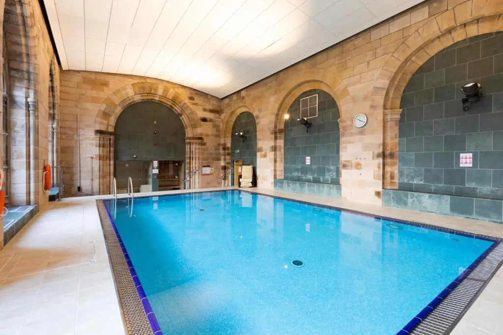 a large swimming pool in a building with a large pool at Cloister View in Fort Augustus