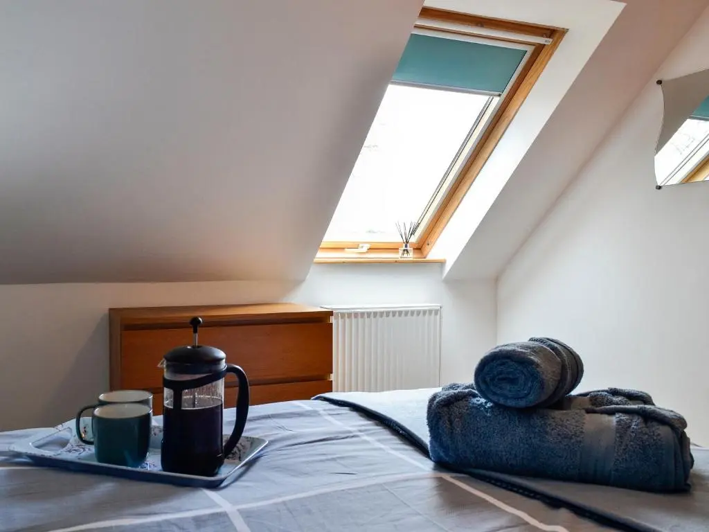 a bed with a tray with two coffee cups and a window at Old Mill Cottage in Blair Atholl