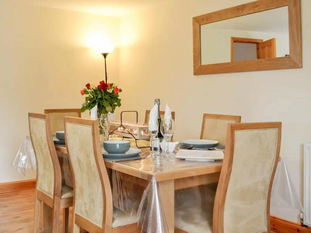 a dining room table with chairs and a mirror at Old Mill Cottage in Blair Atholl
