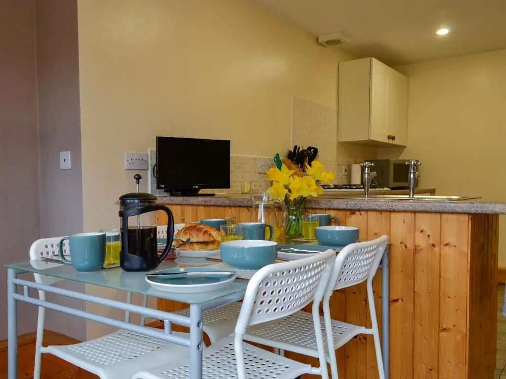 a kitchen with a table with chairs and a counter at Old Mill Cottage in Blair Atholl