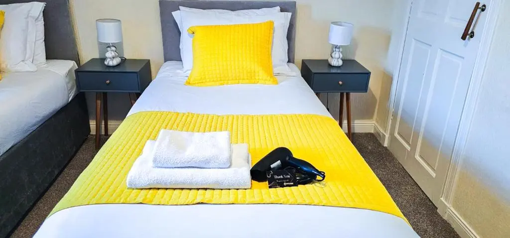 a bedroom with a bed with a yellow blanket at mySTAYINN Telford 7 Bedroom House in Inverness