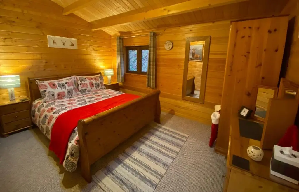 a bedroom with a bed in a log cabin at Cairnhill Lodge - Award-Winning Luxury Highland Retreat in Blairgowrie