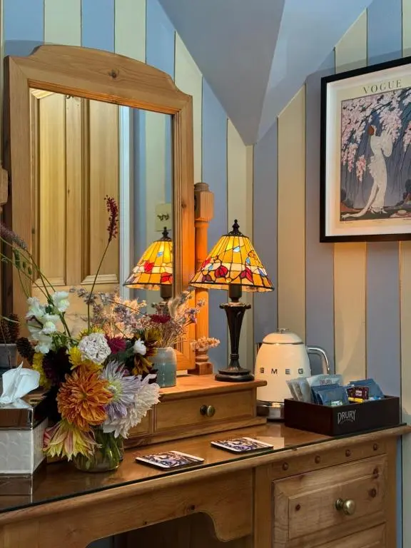 a dressing table with a mirror and flowers on it at Clachan Garden B&B in Garve