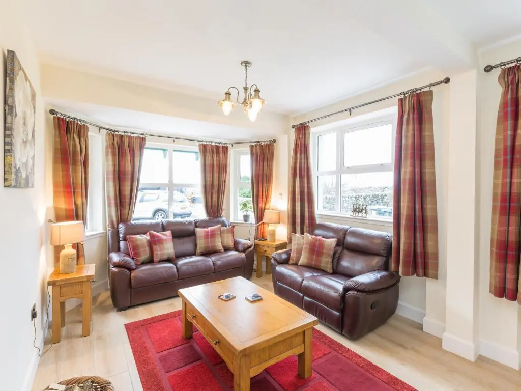 a living room with leather furniture and a table at Chauffeur's Cottage with Hot Tub in Cray