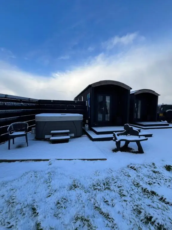 a snow covered yard with a bench and a building at Farr North Lodge 1 By The Sea in Wick