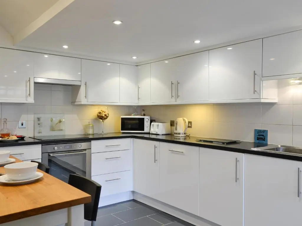 a kitchen with white cabinets and a wooden table at Dee Valley View in Aboyne