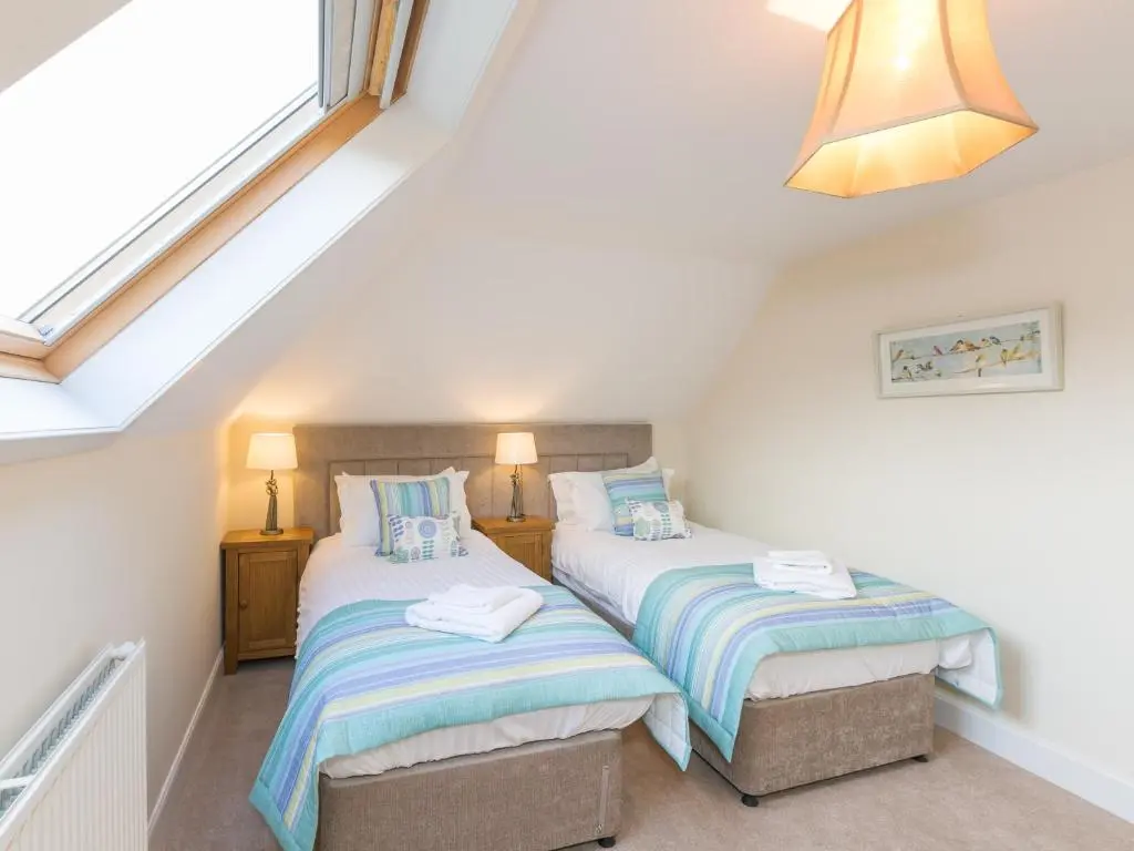 two twin beds in a attic bedroom with a window at Rose Cottage with Hot Tub in Cray