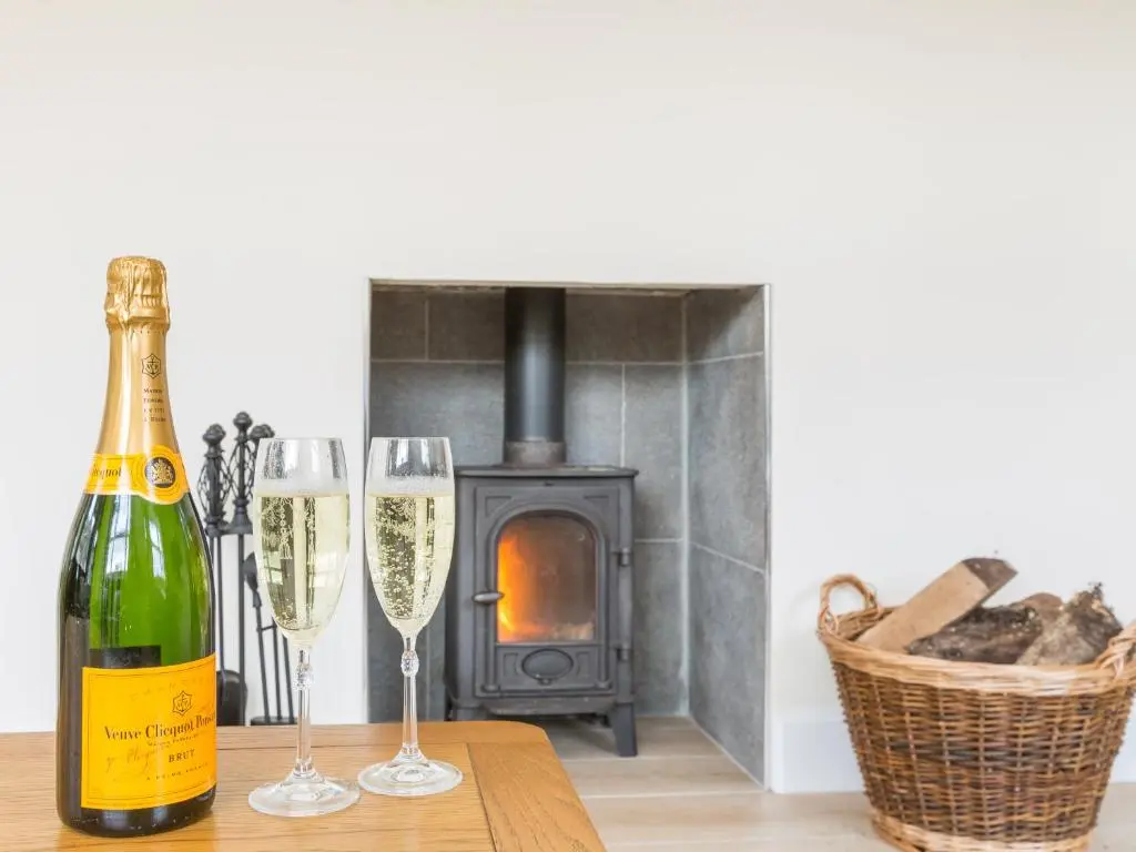 a bottle of champagne and two glasses on a table with a fireplace at Rose Cottage with Hot Tub in Cray