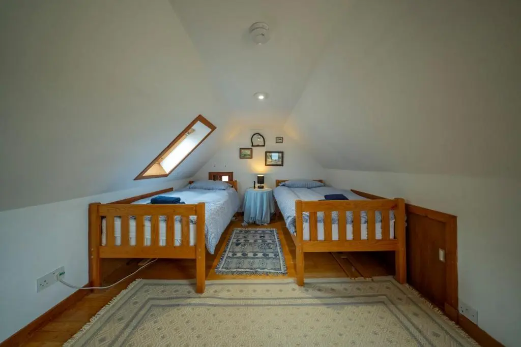 a attic bedroom with two beds and a window at Fisherman's Cottage in Pennan in Pennan