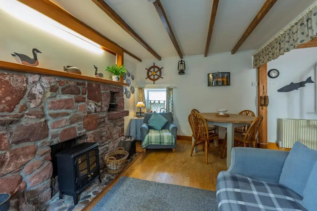 a living room with a stone fireplace and a table at Fisherman's Cottage in Pennan in Pennan