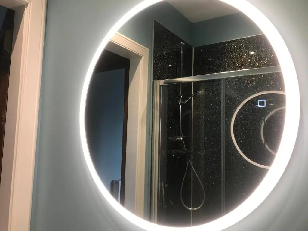a bathroom with a round mirror on a wall at Kenneth Street Apartment in Inverness