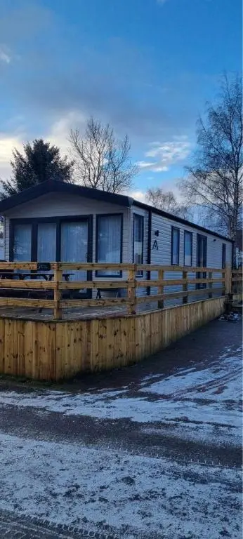 a trailer is parked next to a wooden fence at Dee Lodge in Boat of Garten