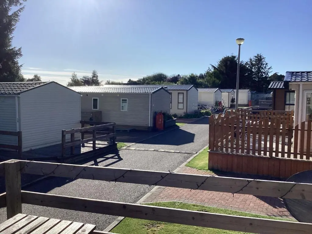 a yard with a fence and some houses at Dee Lodge in Boat of Garten