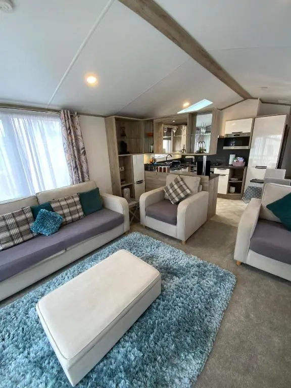 a living room with two couches and a kitchen at Dee Lodge in Boat of Garten