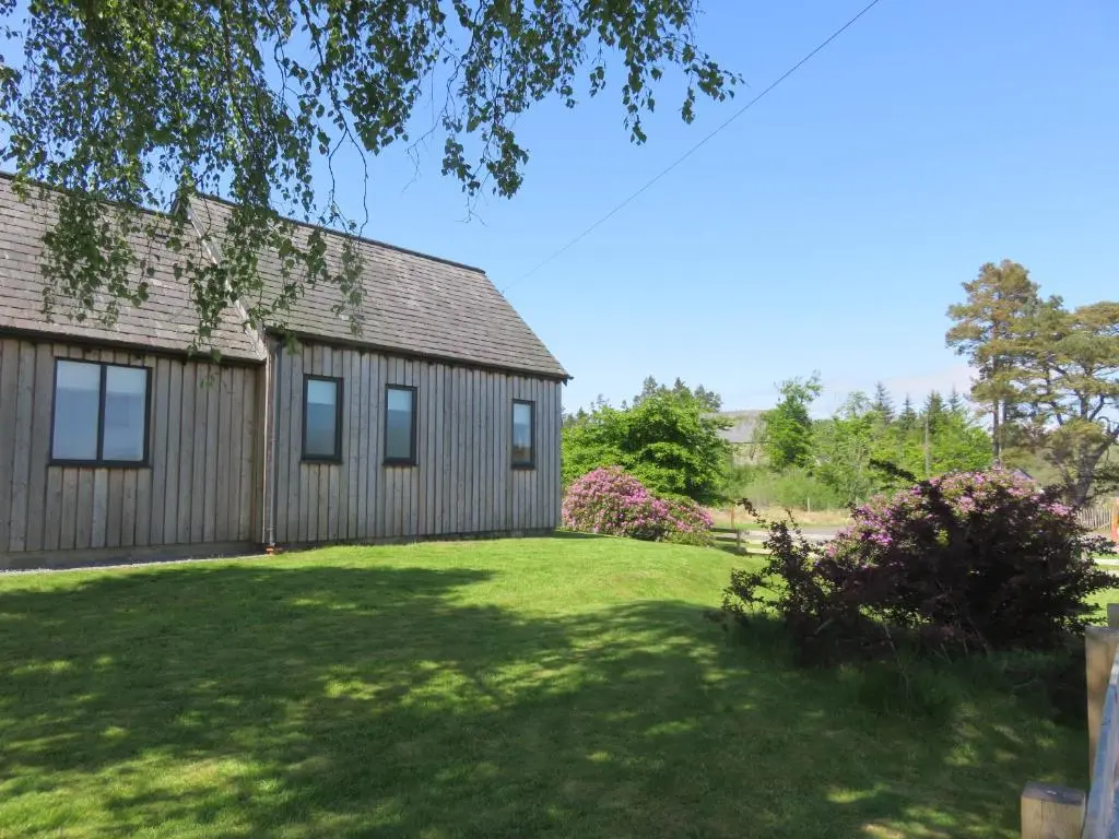 a house with a green yard with a building at Old Schoolhouse in Lairg