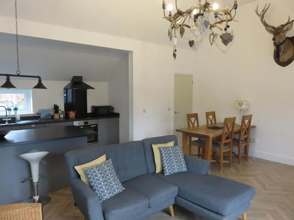 a living room with a blue couch and a table at Old Schoolhouse in Lairg
