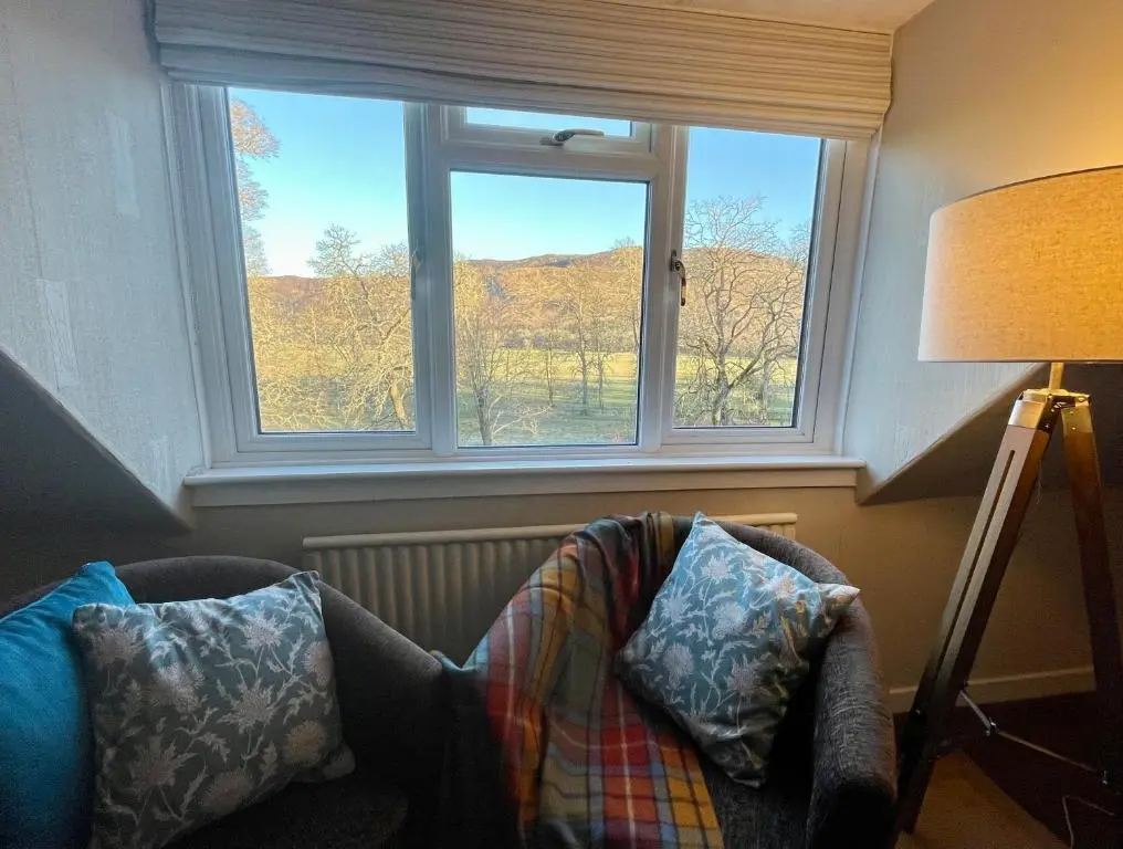 a living room with a chair and a window at The Cnoc Hotel in Beauly