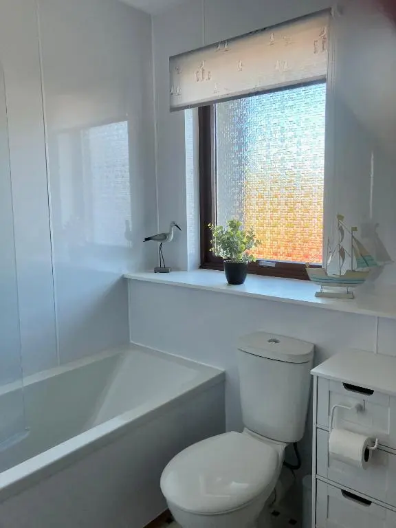 a bathroom with a toilet and a tub and a window at No. 9 in Inverness
