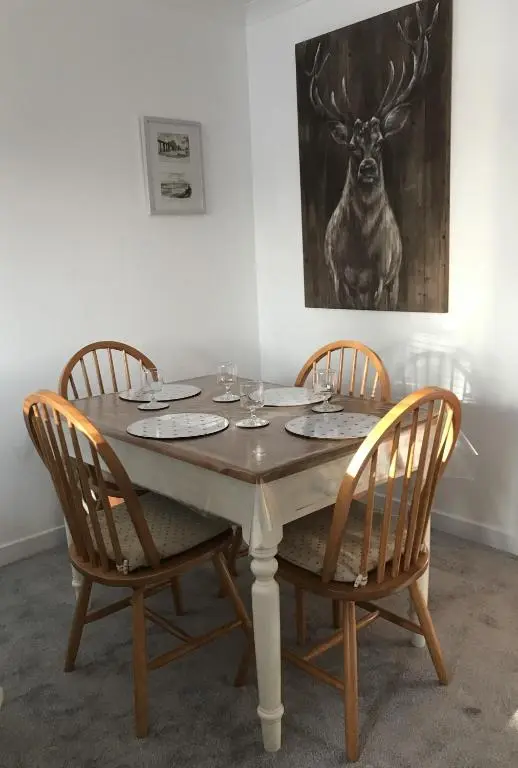a table with four chairs and a picture of a deer at No. 9 in Inverness