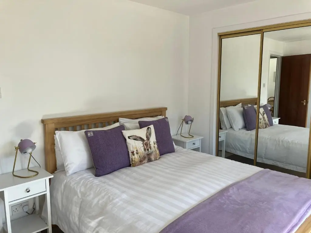 a bedroom with a bed with purple pillows and a mirror at No. 9 in Inverness