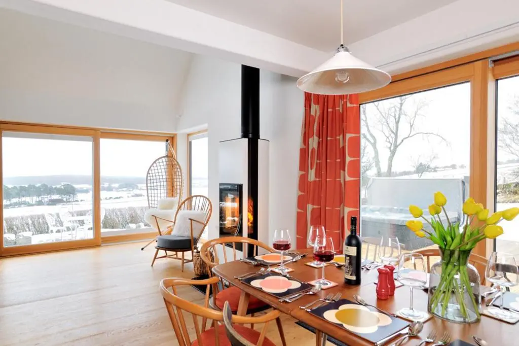 a dining room with a table and chairs and windows at Tom's Lodge in Boat of Garten