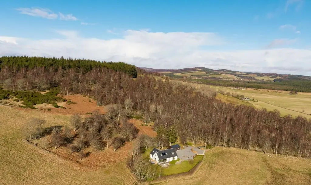 an aerial view of a house in a field at Tom's Lodge in Boat of Garten