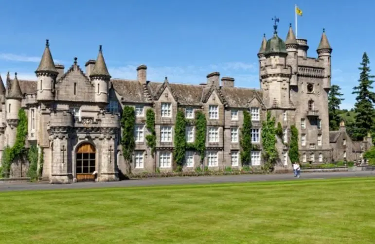 an old castle with a grass field in front of it at Tom's Lodge in Boat of Garten