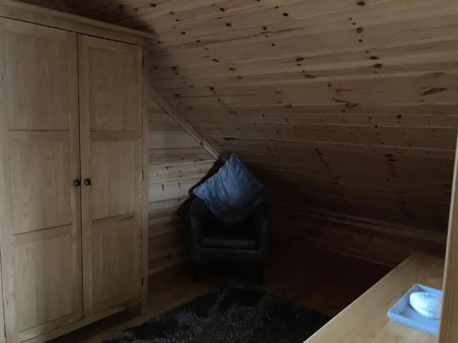 a room with a chair in the corner of a room at Red Squirrel log cabin with hot tub in Keith