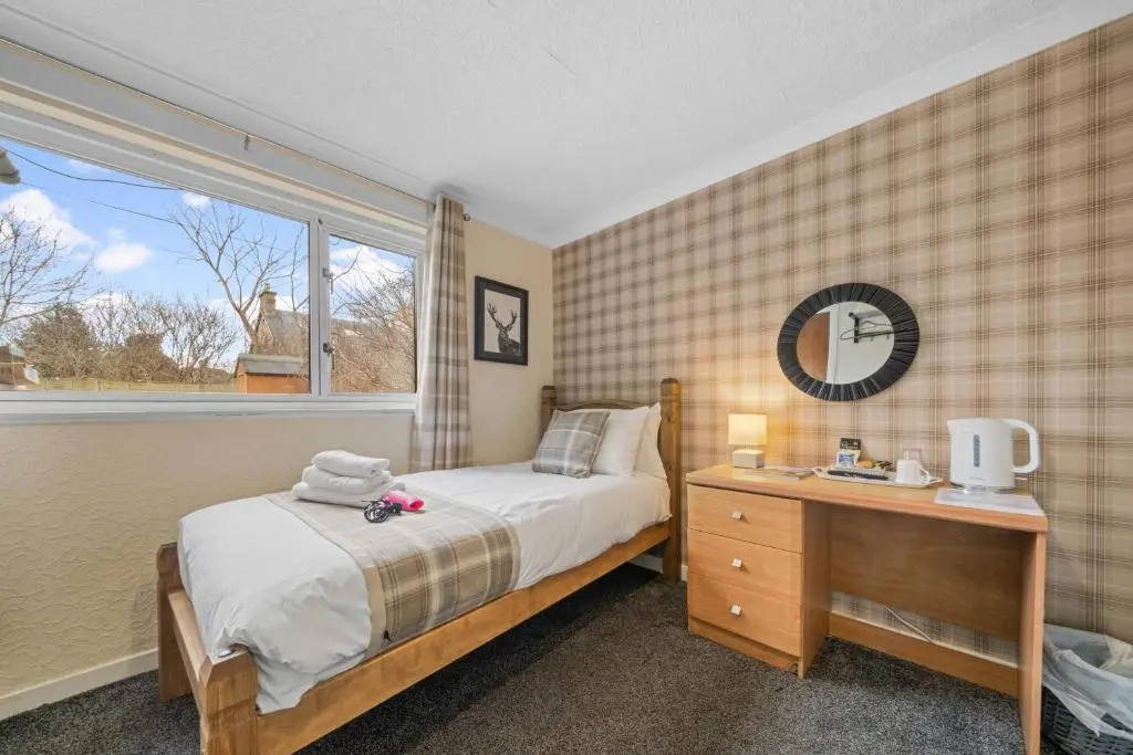 a bedroom with a bed and a desk and a window at mySTAYINN Strathblane 7 Bedroom Full House - Inverness in Inverness