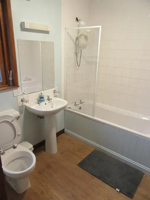 a bathroom with a toilet and a tub and a sink at Kestrel, Longhouse Cottages in Rosemarkie