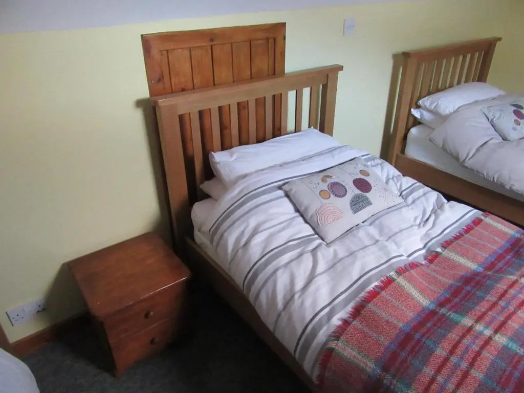 a bedroom with two twin beds and a night stand at Kestrel, Longhouse Cottages in Rosemarkie