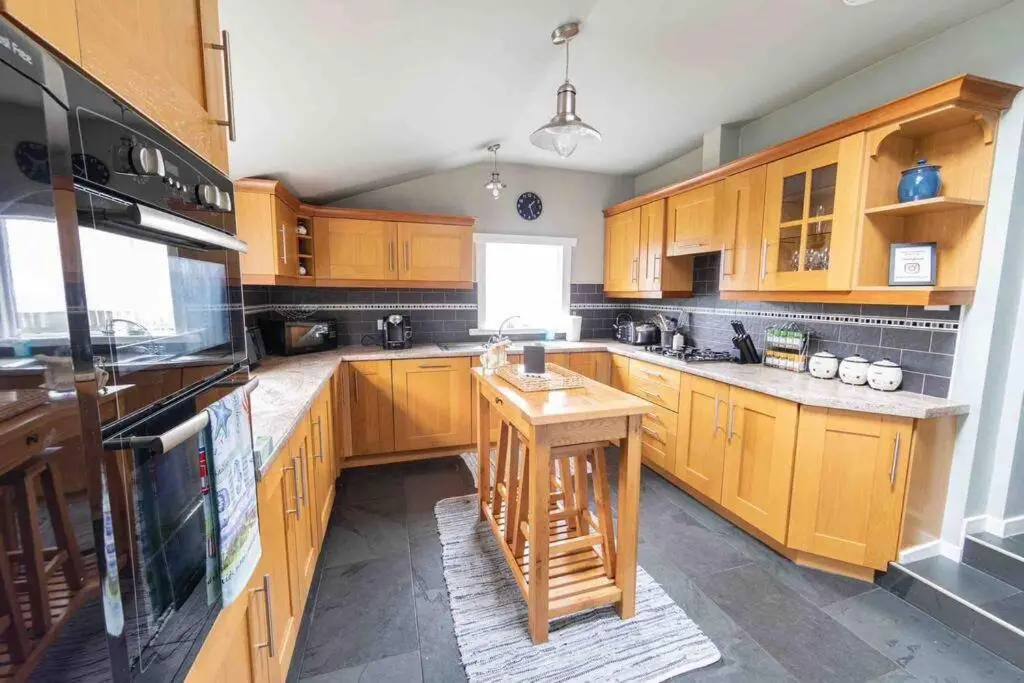 a kitchen with wooden cabinets and a island in it at Hill Crest - Clifftop Escape with Sea View in Cullen