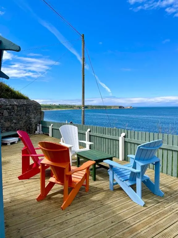 a group of chairs sitting on a deck overlooking the water at Hill Crest - Clifftop Escape with Sea View in Cullen