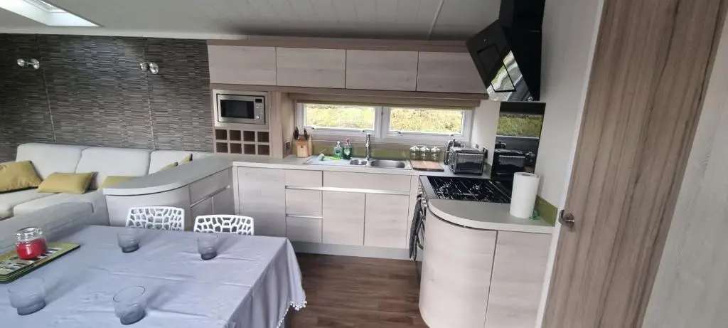 a kitchen and living room with two tables and a couch at Lynton lodges in Evanton