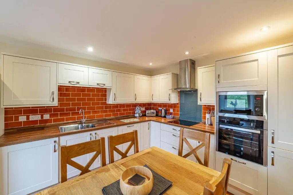 a kitchen with white cabinets and a wooden table at Stags View with Hot Tub in Blairgowrie