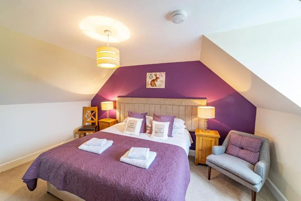 a bedroom with a purple bed and a chair at Stags View with Hot Tub in Blairgowrie