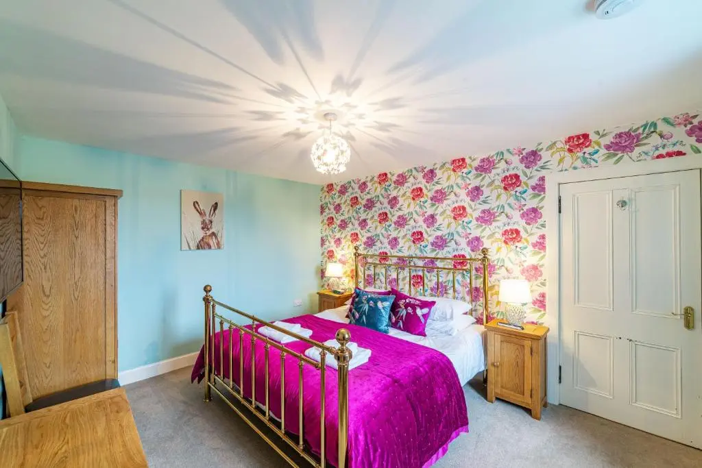 a bedroom with a bed with a pink bedspread at Stags View with Hot Tub in Blairgowrie