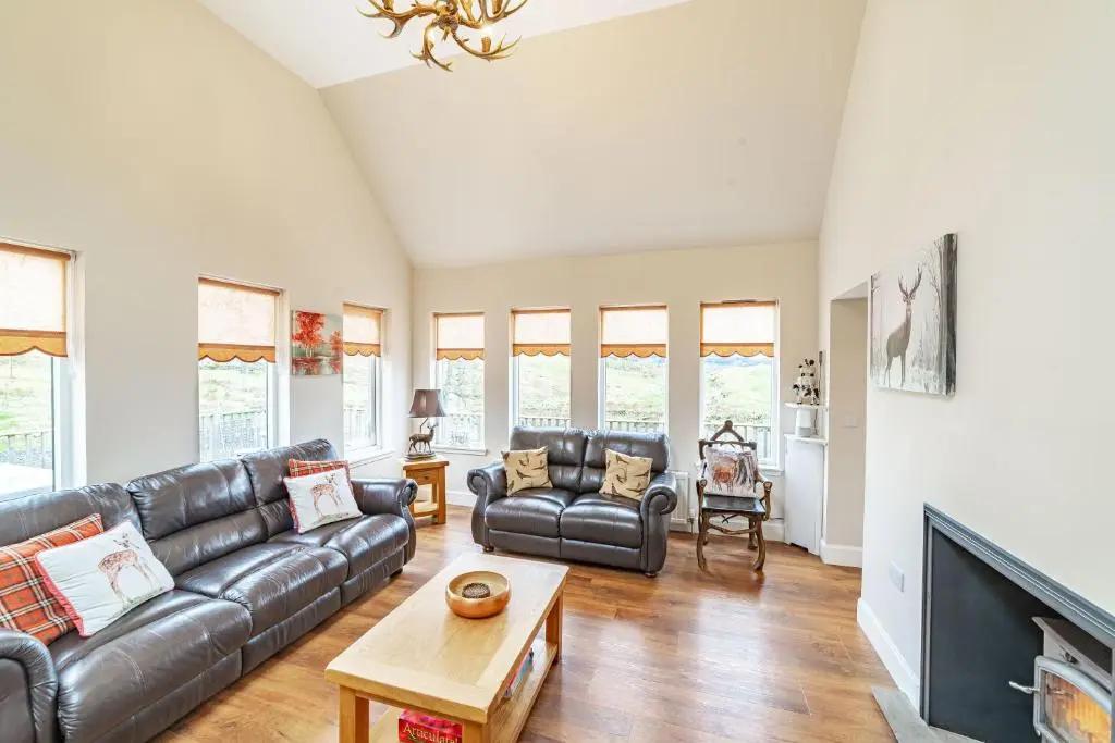 a living room with a leather couch and a table at Stags View with Hot Tub in Blairgowrie