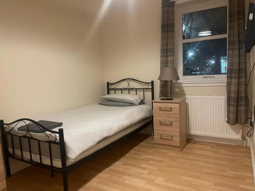 a bedroom with a bed with a lamp and a window at Morlich Guesthouse in Dingwall