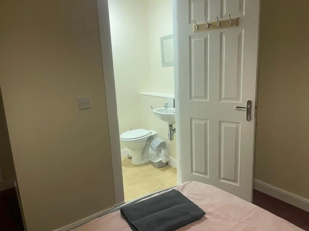 a bathroom with a bed and a toilet and a door at Morlich Guesthouse in Dingwall