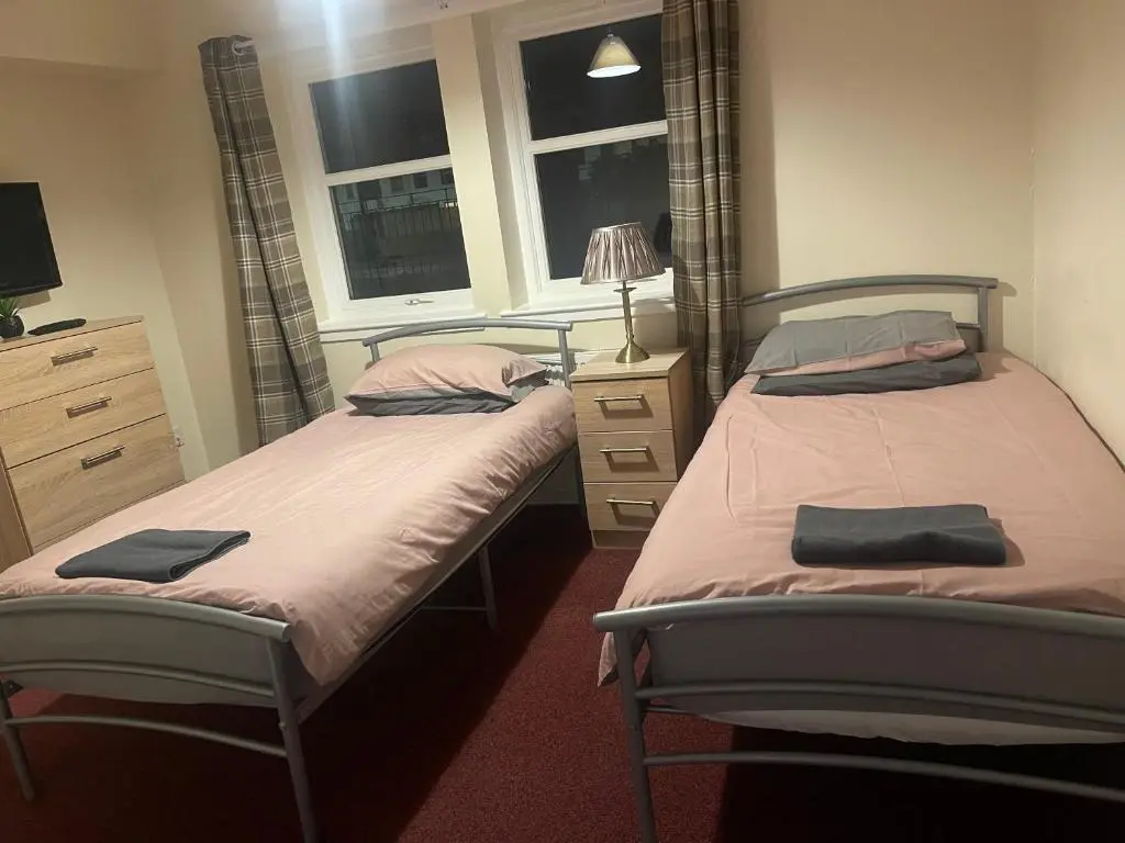 two twin beds in a room with two windows at Morlich Guesthouse in Dingwall