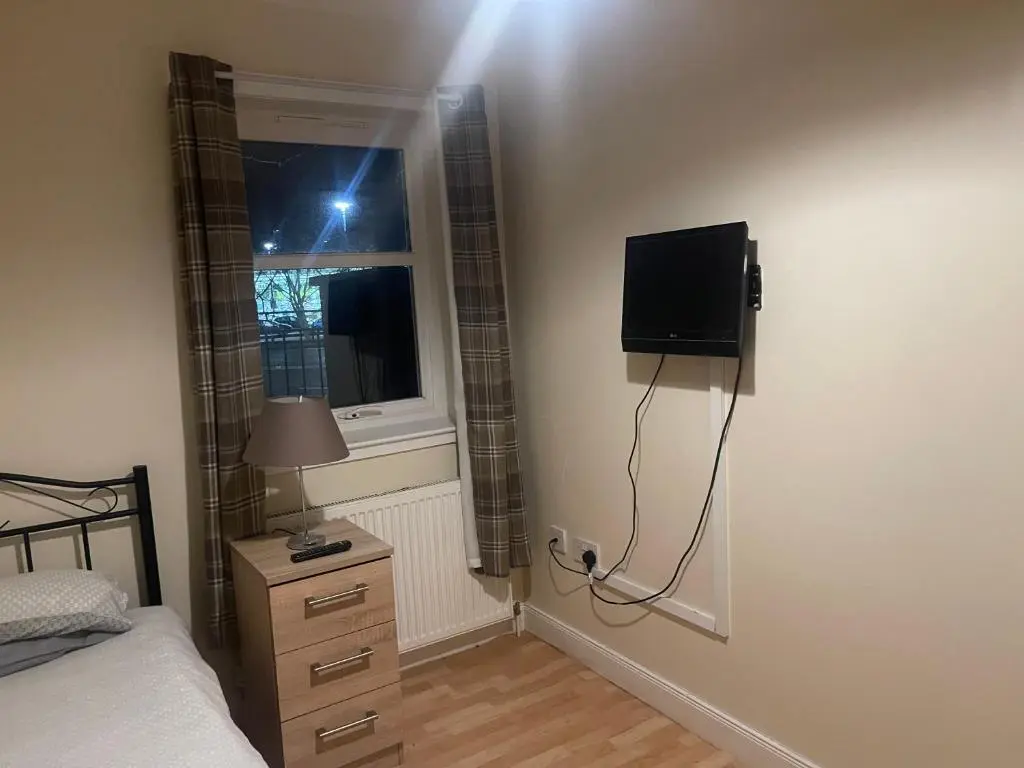 a bedroom with a bed and a television on the wall at Morlich Guesthouse in Dingwall