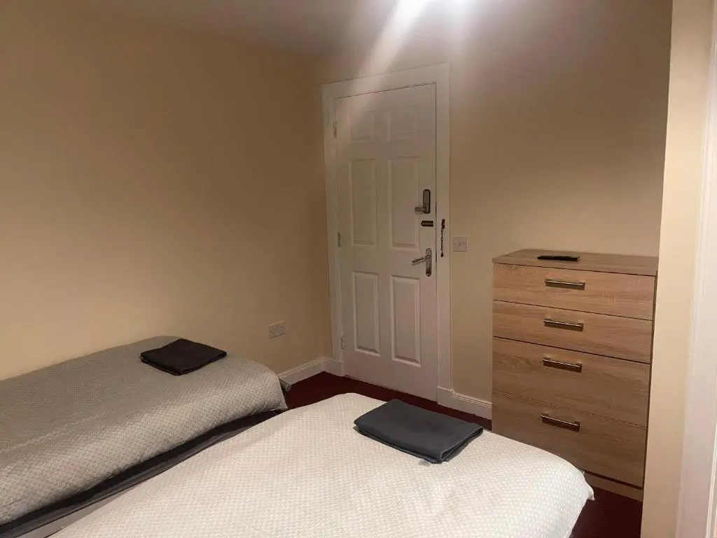 a bedroom with two twin beds and a dresser at Morlich Guesthouse in Dingwall
