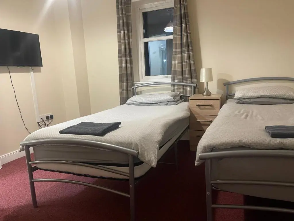 two twin beds in a room with a window at Morlich Guesthouse in Dingwall
