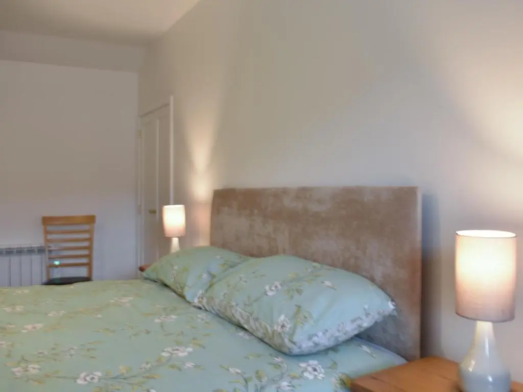 a bed with two lamps and a pillow on it at Rinnes Cottage in Aberlour