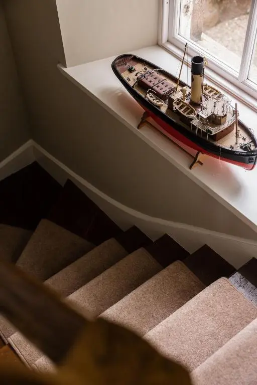 a model boat sitting on a shelf next to a window at North Lodge & River Cabin in Banchory