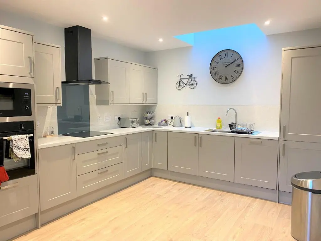 a kitchen with white cabinets and a clock on the wall at The Stables with Hot Tub in Cray