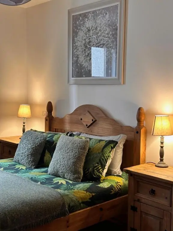 a bedroom with a wooden bed with two lamps at City centre apartment next to Bus and Train Station in Inverness