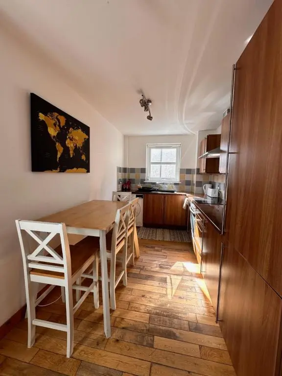 a kitchen with a table and chairs and a refrigerator at City centre apartment next to Bus and Train Station in Inverness